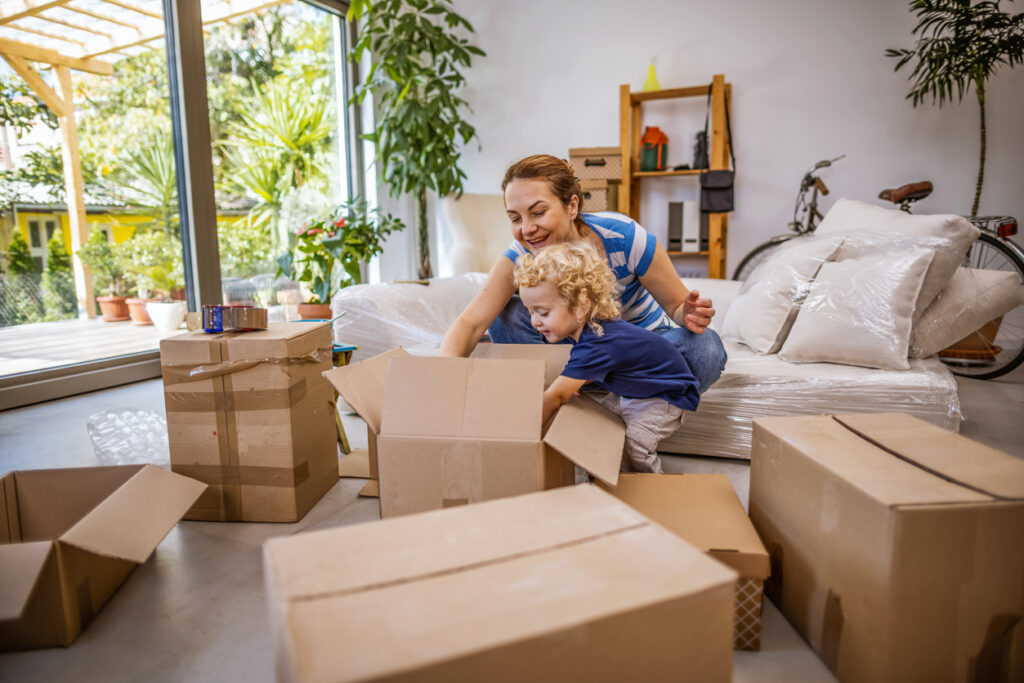 Two people unpack boxes in bright, modern room with couch and bike.